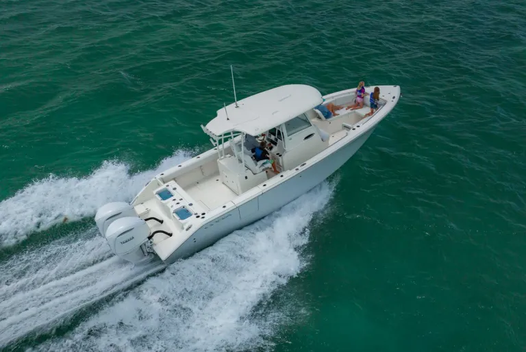 Aerial stern-quarter drone shot of Cobia 320 CC with family and Yamaha outboards running in Florida Keys