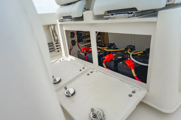 Cobia 320 CC under-seat battery compartment open showing four 31-series marine batteries with sealed wiring harness