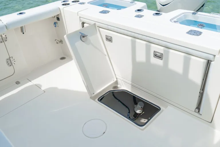 Cobia 320 CC bilge access hatch open revealing bilge pump components, with cockpit livewell and transom storage visible
