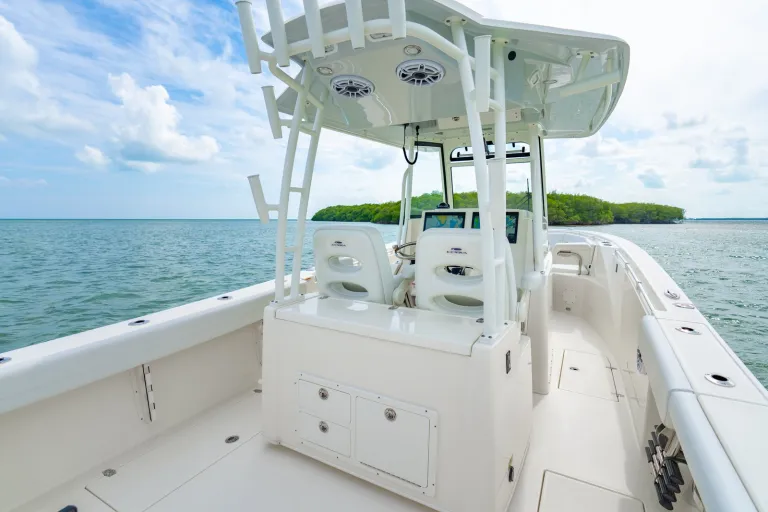 Cobia 320 CC cockpit from port-forward angle showing full helm, hardtop with JL Audio speakers, Cobia seats, and bow lounge