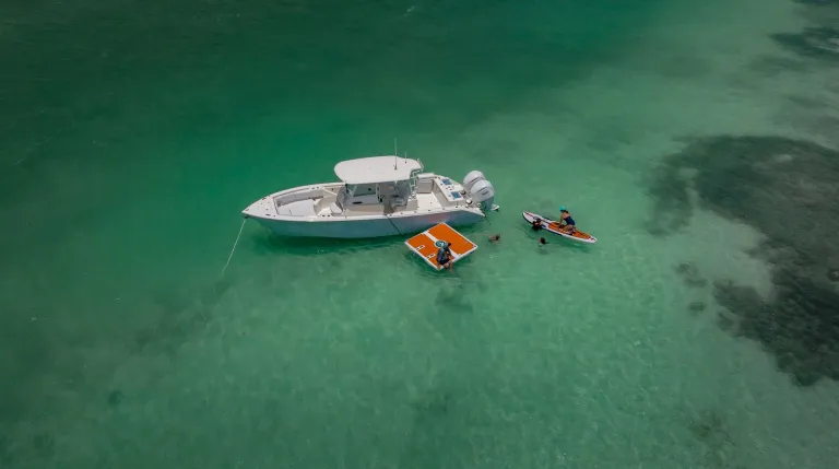 Drone aerial shot of white Cobia 320 CC center console running over open blue offshore water