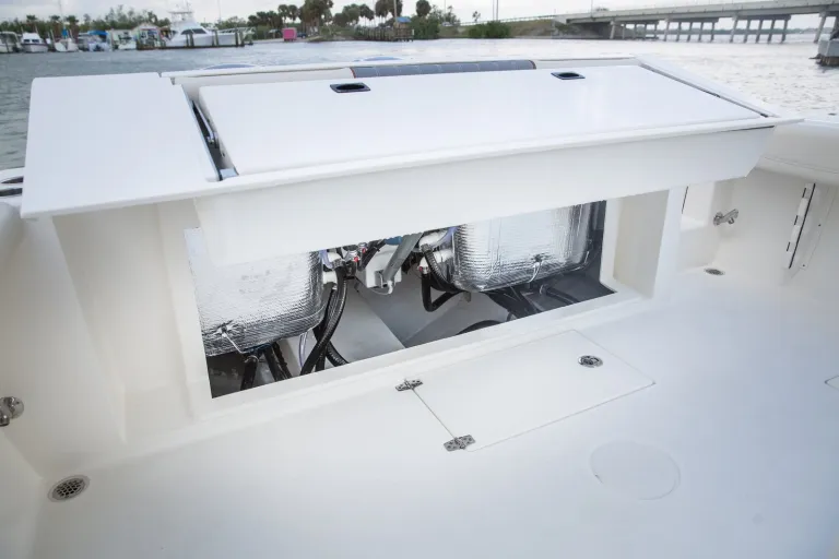 Cobia 320 CC engine compartment access hatch open revealing twin engine mechanical systems and insulated plumbing lines