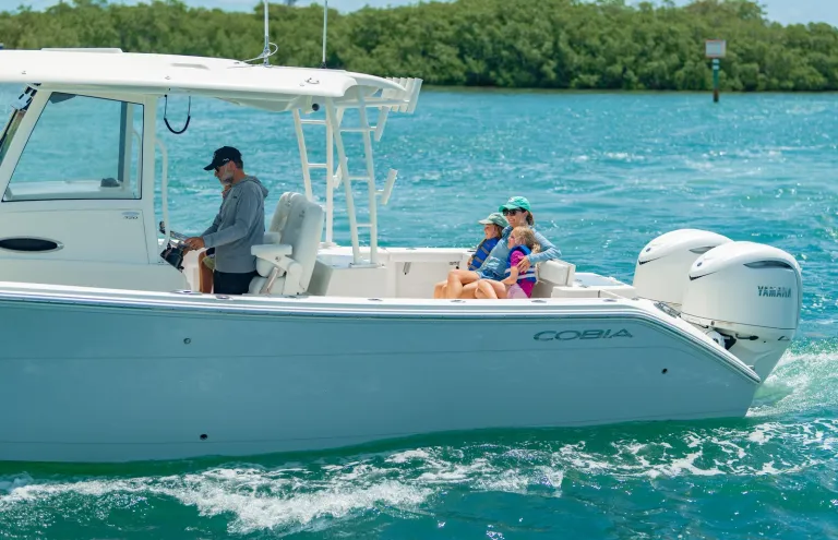 Cobia 320 CC family lifestyle shot near Florida mangroves with dad at helm and family in cockpit