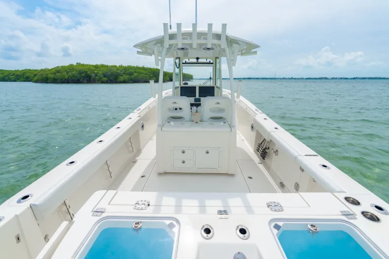 Cobia 320 CC full cockpit view from transom looking forward with dual livewells in foreground, center console, and hardtop