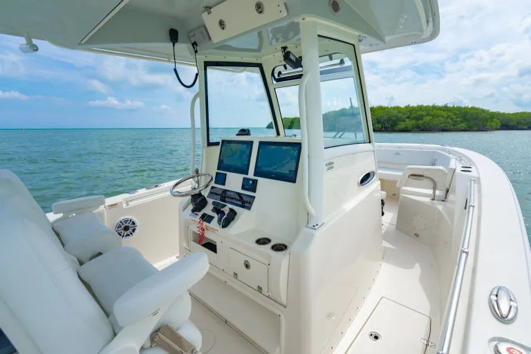 Cobia 320 CC helm console showing dual Garmin chart plotters, glass windshield, 320 model badge, and Cobia captain's chairs