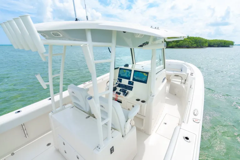 Cobia 320 CC helm and console from port-side angle showing captain's seats, Garmin electronics, hardtop, and outriggers
