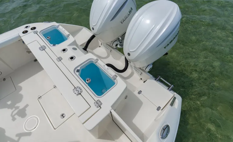 Overhead angle of Cobia 320 CC transom with twin Yamaha outboards and open livewells visible over clear green water