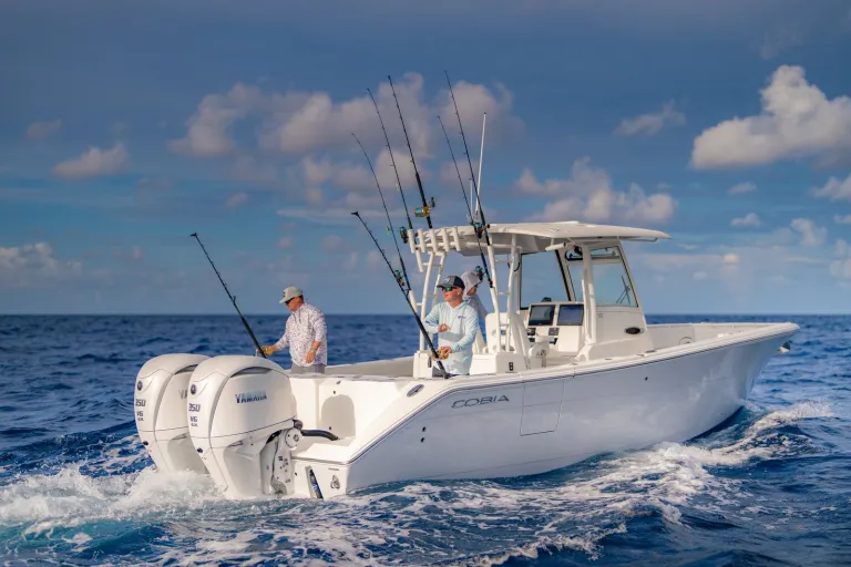 Cobia 320 CC port-stern with two anglers fishing and twin Yamaha 350 outboards running offshore