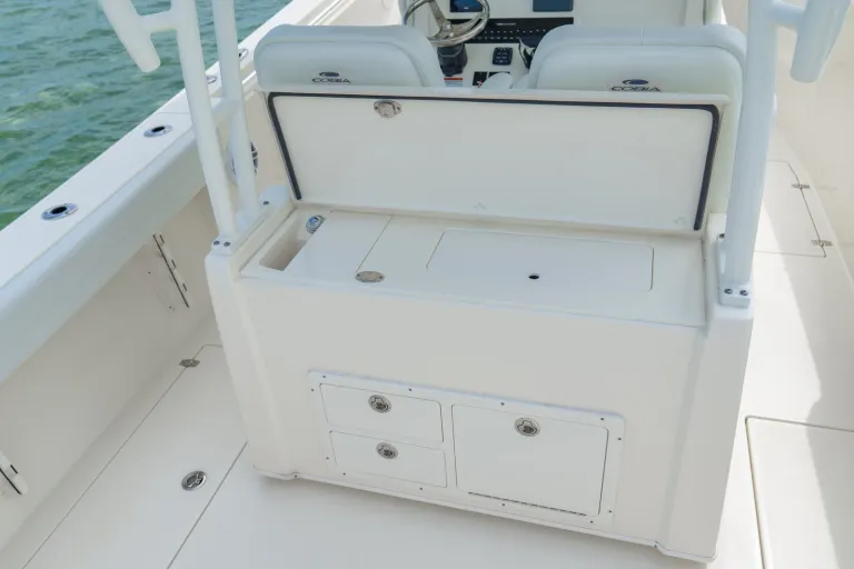 Cobia 320 CC tackle center open showing bait prep surface, tackle tray storage compartments, and lower drawers in cockpit