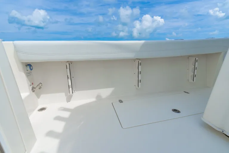 Cobia 320 CC under-gunnel rod storage rail with multiple stainless steel rod holders beneath cushioned gunnel bolster