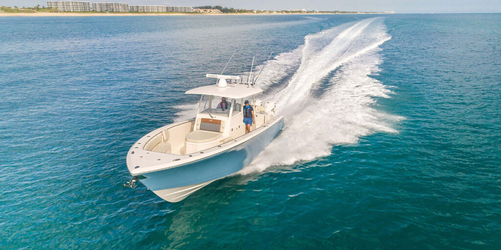 Cobia 350 Center Console with white Yamaha Twin Engines running with beach in the background.